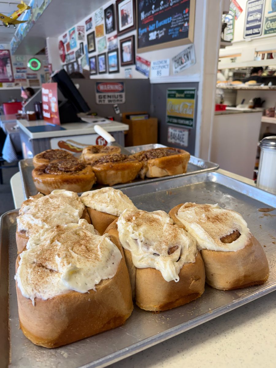 Trays of frosted cinnamon rolls and pecan rolls on the diner counter