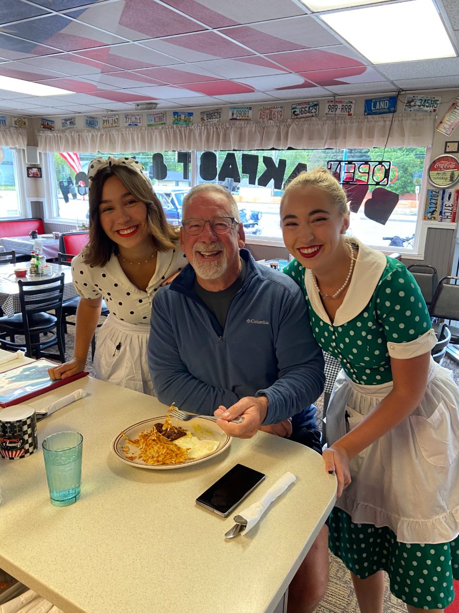 Jimmy laughing at the counter with two servers in vintage diner uniforms