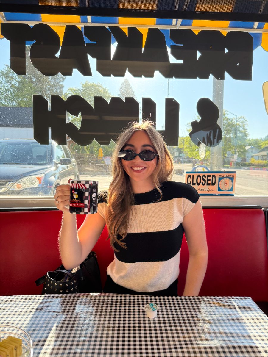 Jimmy's daughter Maria raising a checkerboard Jimmy's Down the Street mug in a red booth